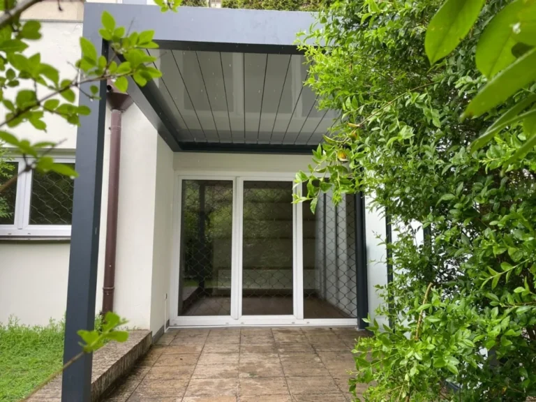 Hliníková pergola s lamelovou střechou u vstupu do domu